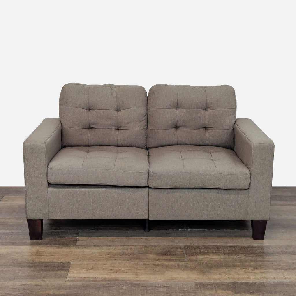 1. Front view of Amazon loveseat with taupe tufted upholstery and tapered wood block feet on wooden floor.
