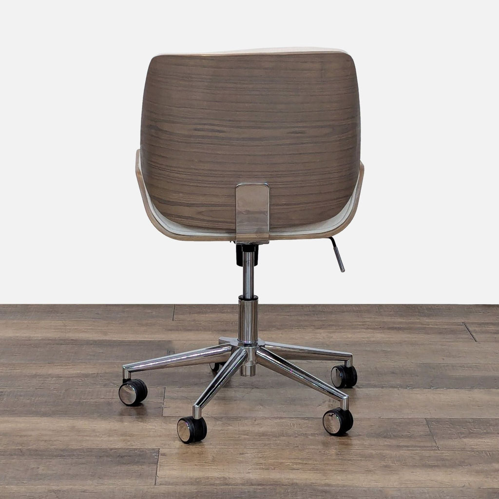 3. Rear view of Crate & Barrel chair with curved wood back, cream upholstery edges, and five-legged caster base.