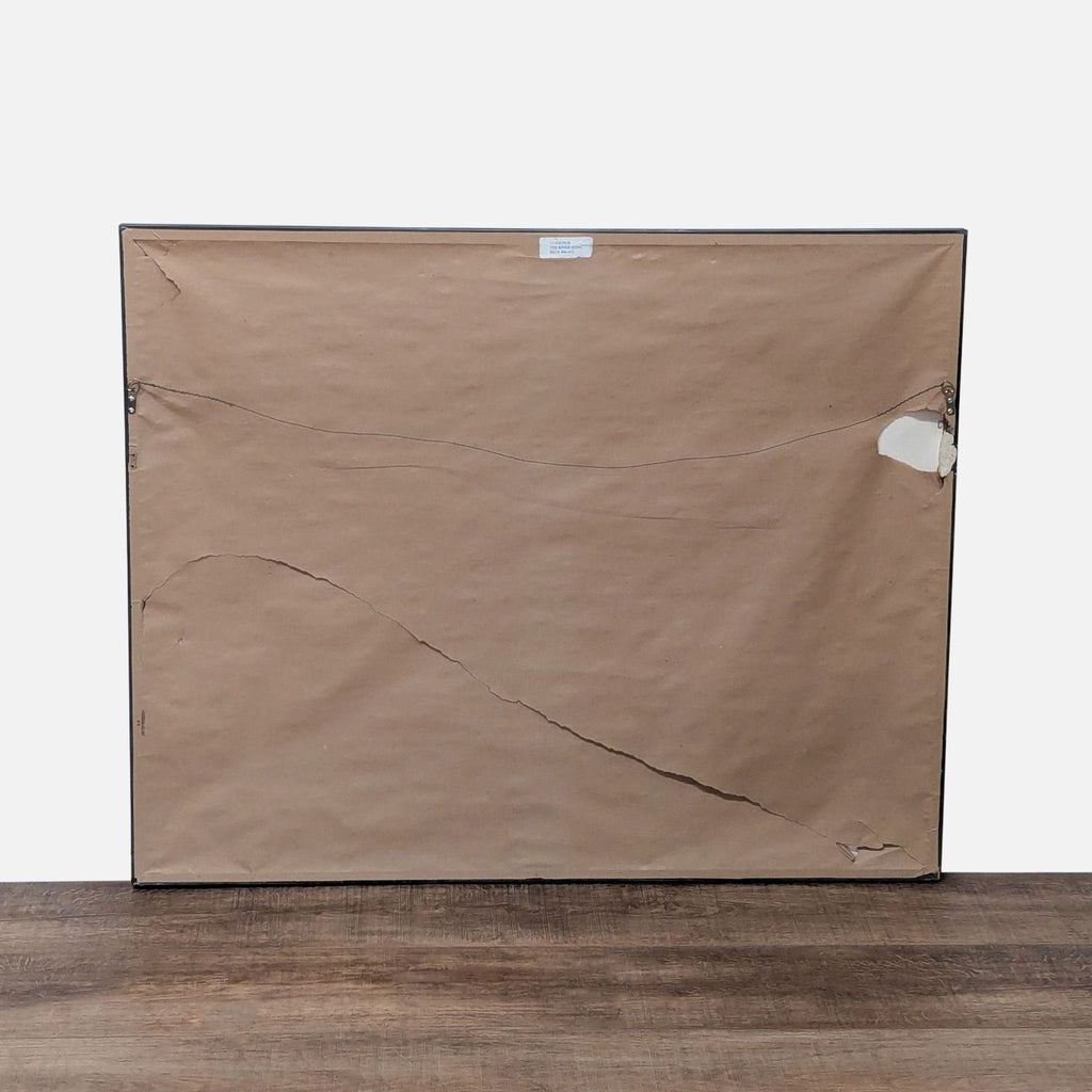 2. Back view of the framed River Seine print, showing brown paper backing with tears and a hanging wire.