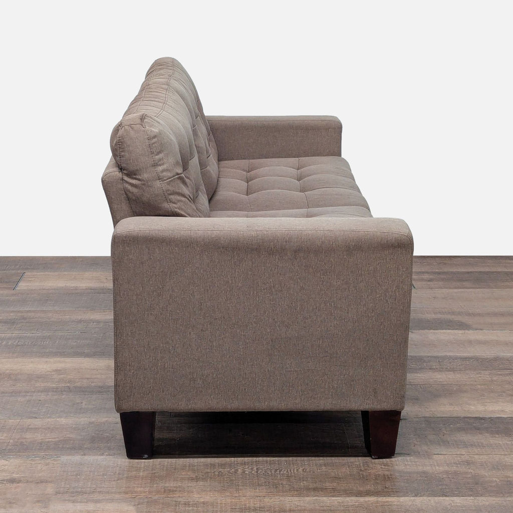 2. Side profile of a taupe Amazon loveseat showing tufted cushions and wooden block legs.