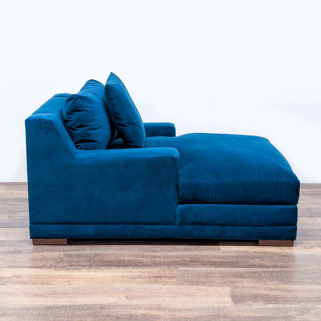 Side view of a blue Living Spaces chaise featuring soft foam and fiber seating with wooden block feet.  