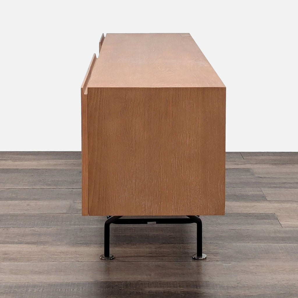 3. Side profile of a minimalist oak credenza with white cerused finish and sleek black metal legs.