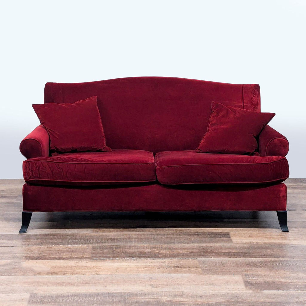 1. Crate & Barrel loveseat with rolled arms, red velvet upholstery, wood feet, and two matching cushions, front view.