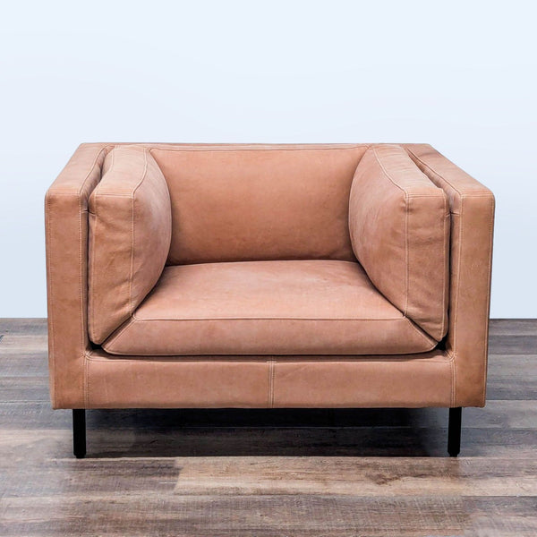 1. Tan leather lounge chair by Arhaus with deep seat, square arms, plush cushions, and black metal legs, front view.
