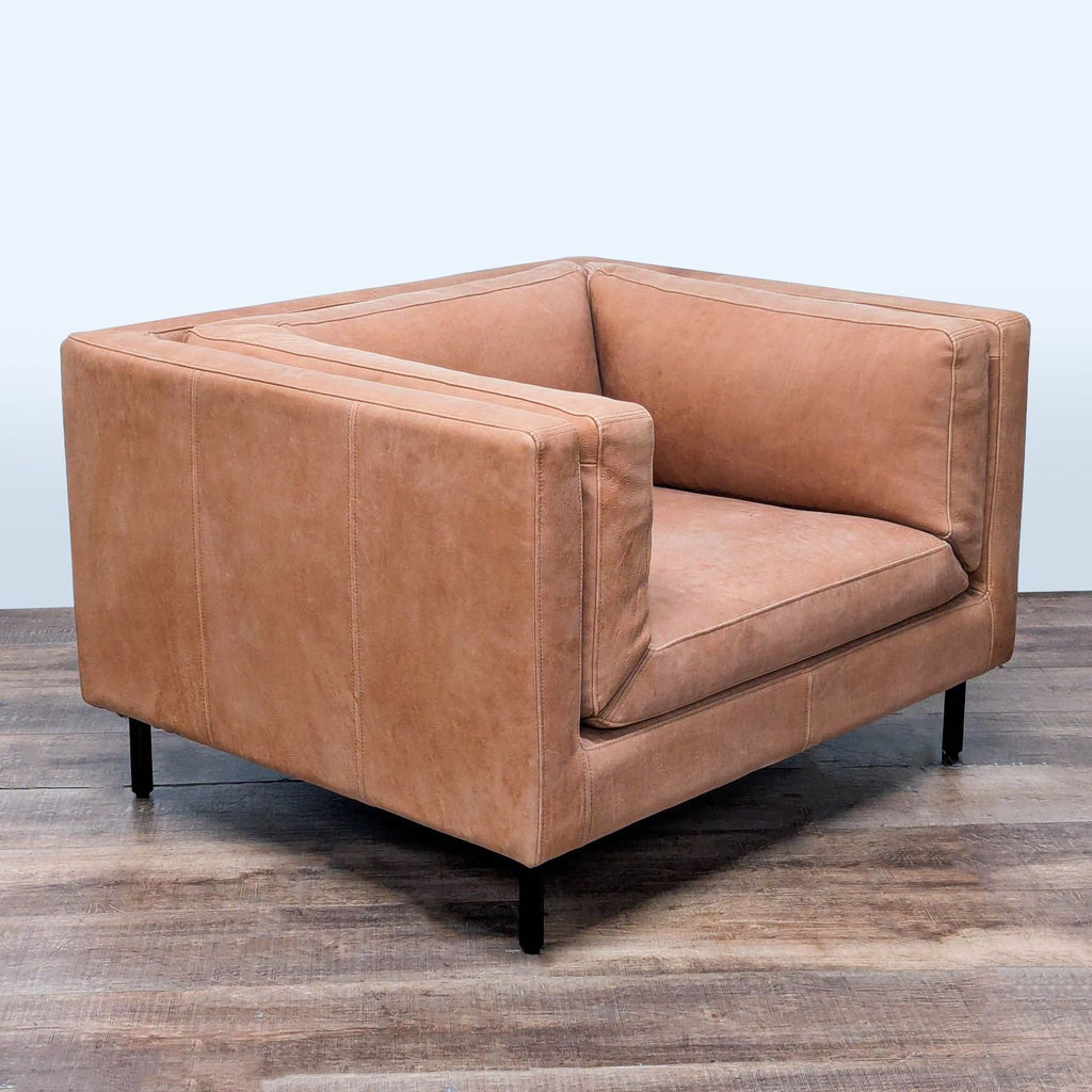 3. Angled view of Arhaus tan leather lounge chair with plush side cushions, square arms, and modern black metal legs.