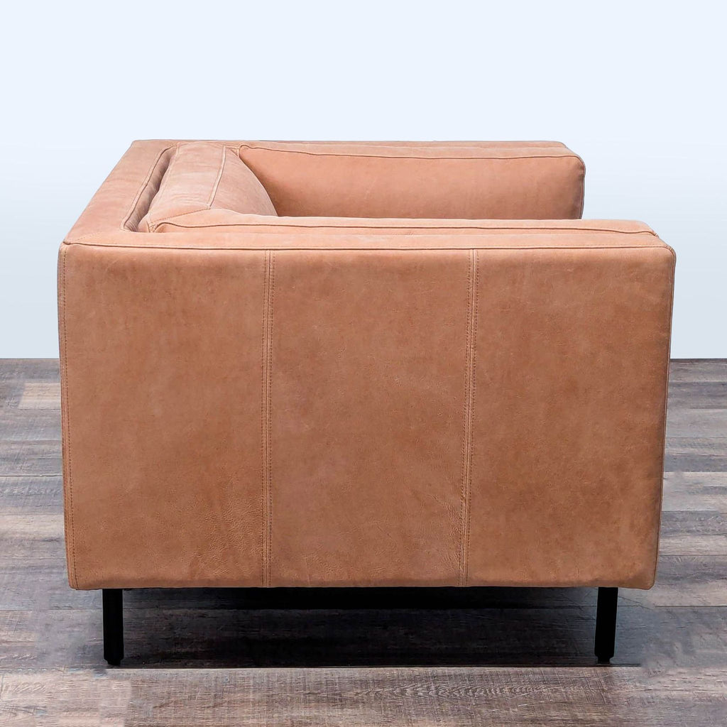 2. Side view of Arhaus tan leather lounge chair showing sleek lines, square arms, and slim black metal legs.