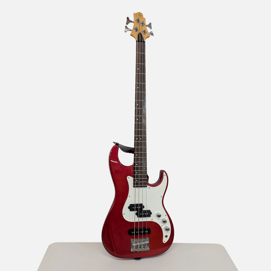 Corsair electric bass guitar with a glossy red finish, four strings, and a white pickguard, standing upright.