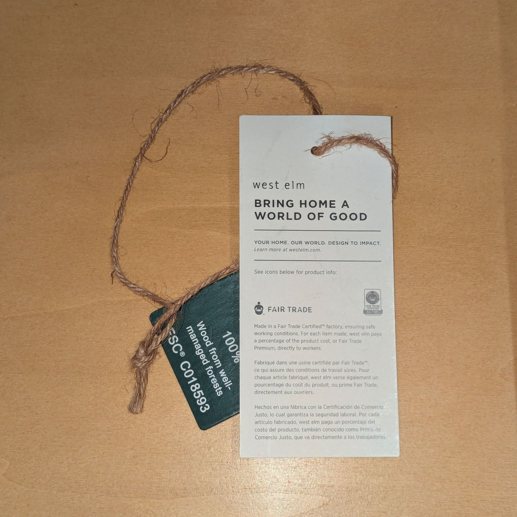 3. West Elm branded tag highlighting fair trade certification and sustainable wood used for this dresser product.