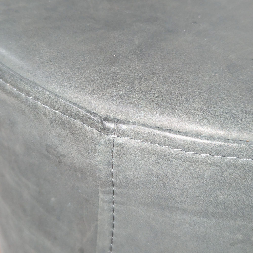 3. Close-up of Blu Dot ottoman’s gray leather upholstery with detailed stitching on the seam.