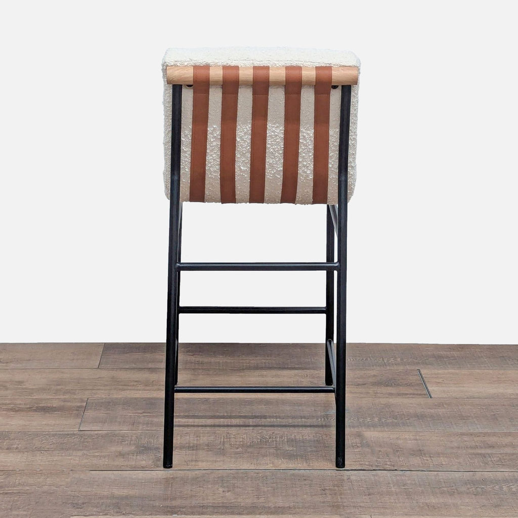 2. Back view of Lilola Home boucle stool featuring Cognac PU leather straps and a wood-like bar on black legs.  