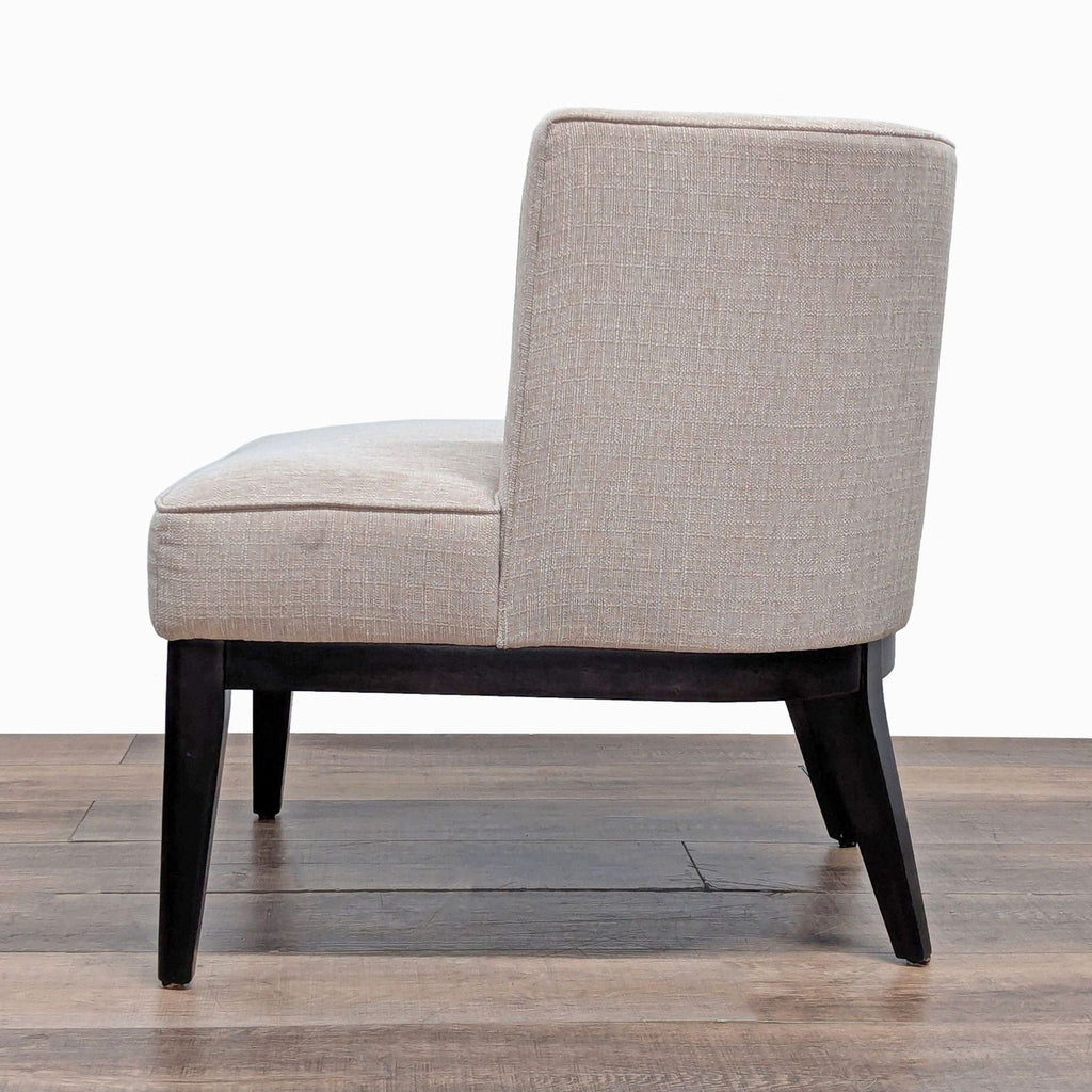 3. Lounge chair by Crate and Barrel in beige upholstery, wood legs, and curved barrel back, side profile.