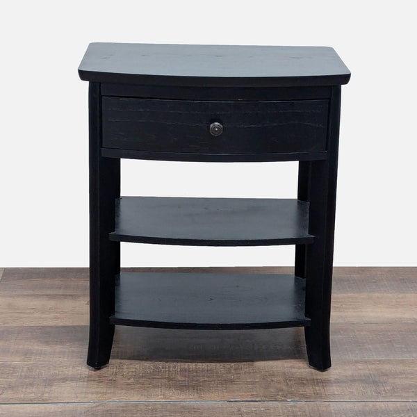 1. Black Pottery Barn end table with a single drawer and two lower shelves, set on a wood floor.