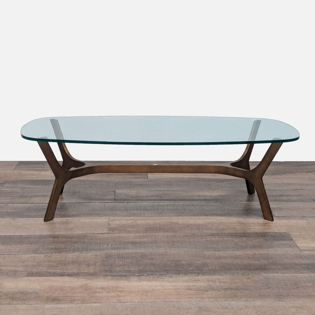 1. Crate & Barrel coffee table with a clear glass top on a modern brass base, shown on a wooden floor.  