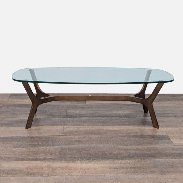 1. Crate & Barrel coffee table with a clear glass top on a modern brass base, shown on a wooden floor.  