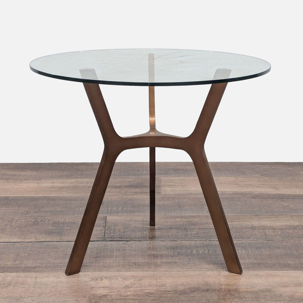1. Crate and Barrel end table with a round glass top and sculpted brass base, shown on wood flooring.