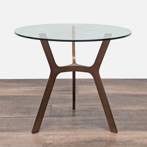 1. Crate and Barrel end table with a round glass top and sculpted brass base, shown on wood flooring.