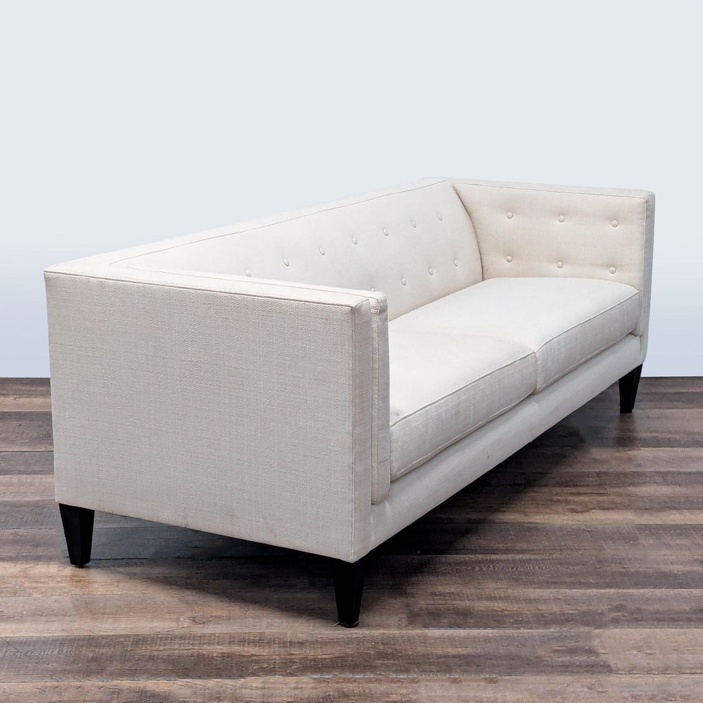 3. Angled view of a Crate and Barrel 3-seat sofa with button-tufted back and sleek tuxedo framing.