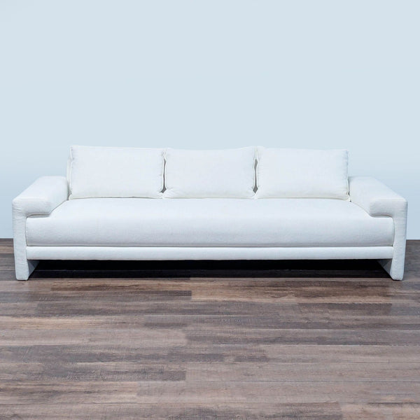 1. Modern CB2 3-seat sofa in white fabric, featuring wide arms and three back cushions on wood flooring.