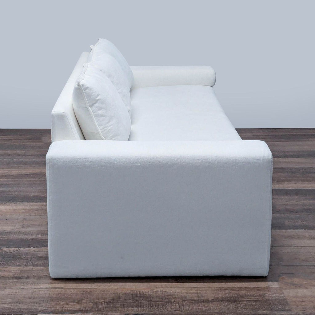 3. Side profile of a white CB2 3-seat sofa showing clean lines, wide armrest, and simple contemporary style.