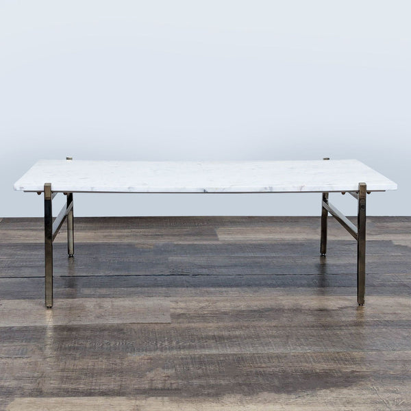 1. CB2 coffee table with a white marble top and metal base, shown on a wooden floor, front view.