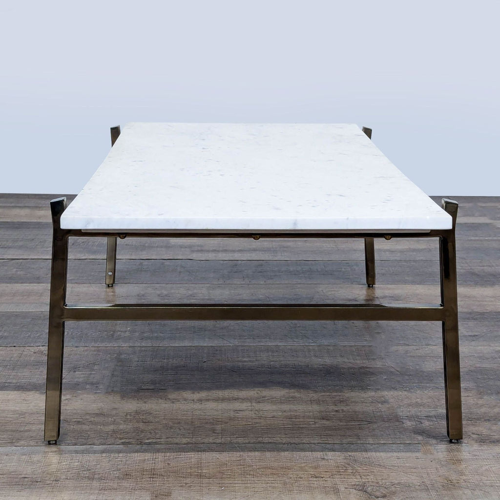 3. Rectangular CB2 coffee table with a marble top and sturdy metal base, viewed from the short end.