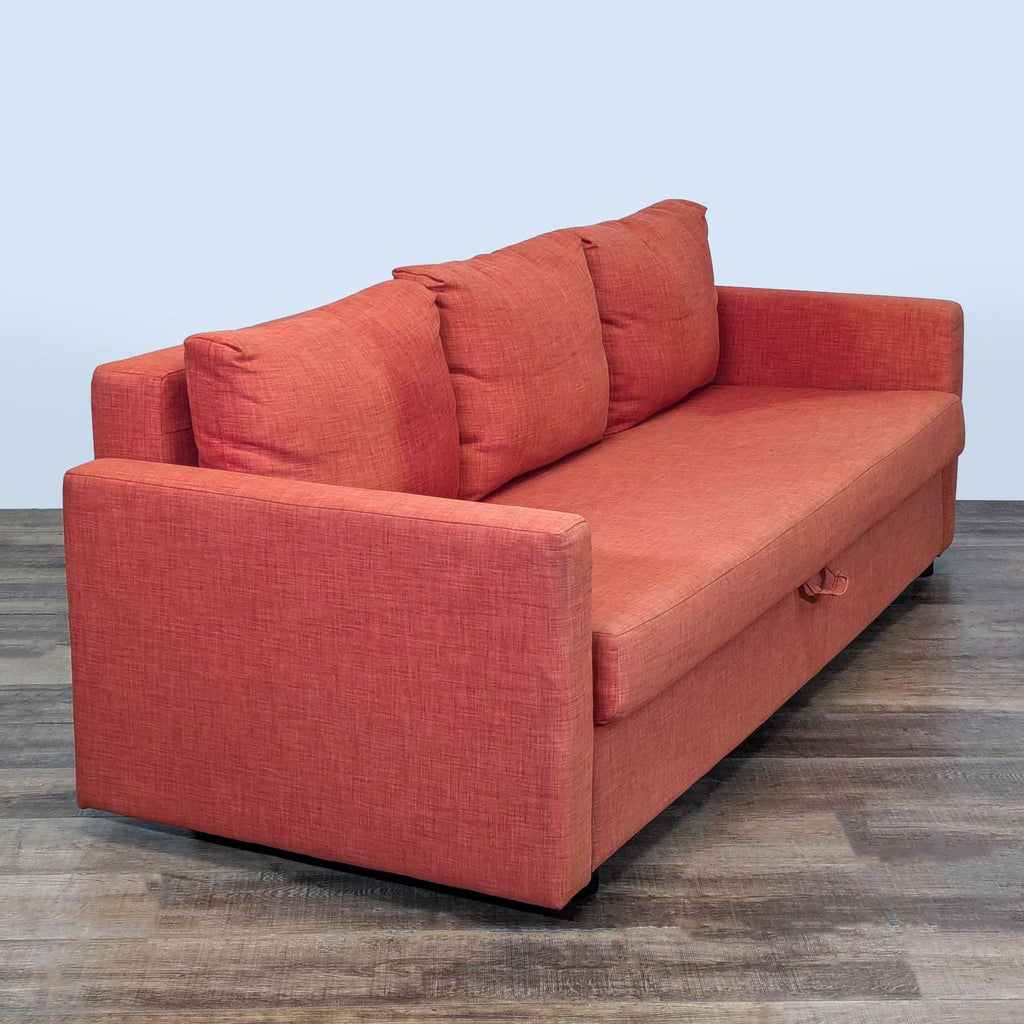 3. Angled view of orange 3-seat Ikea sleeper sofa with three cushions and hidden bedding storage.