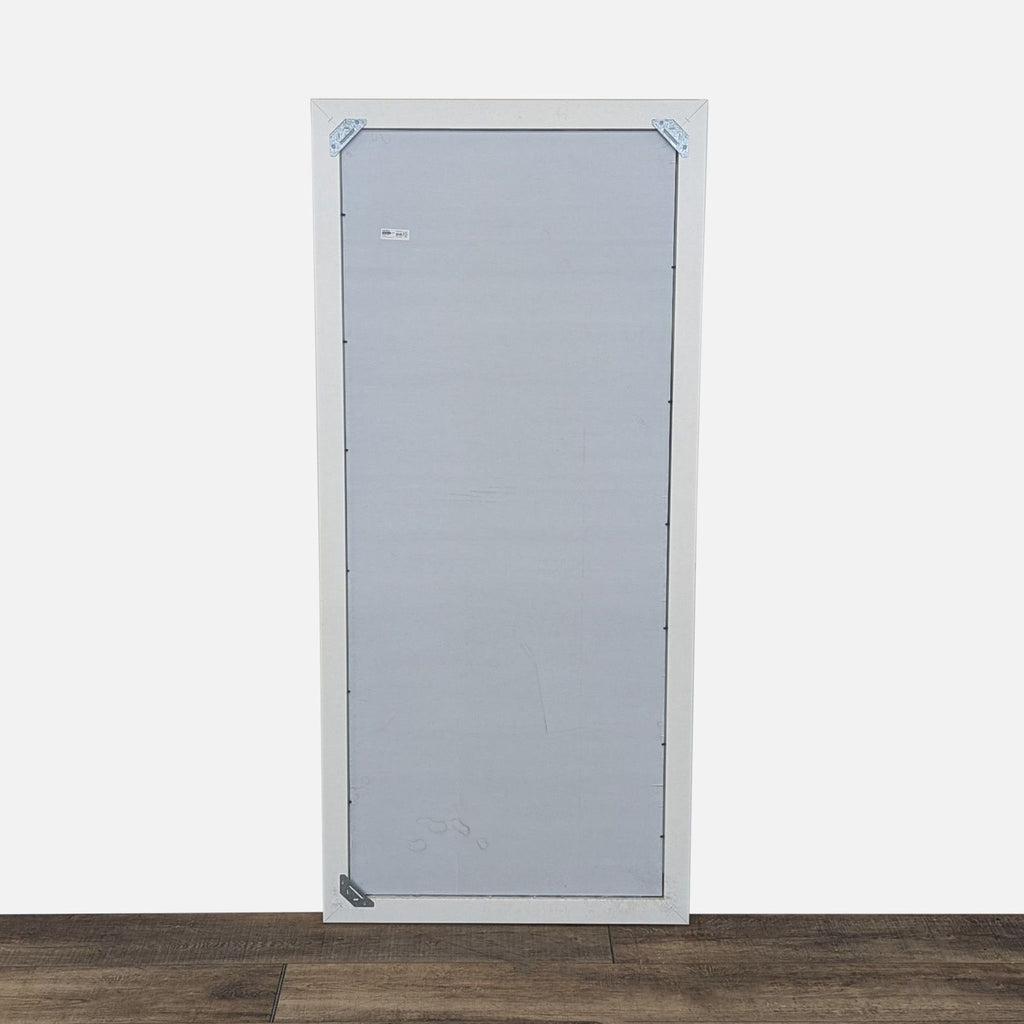 2. Back view of the Ikea mirror displaying its white outer frame, gray backing, and metal corner brackets.