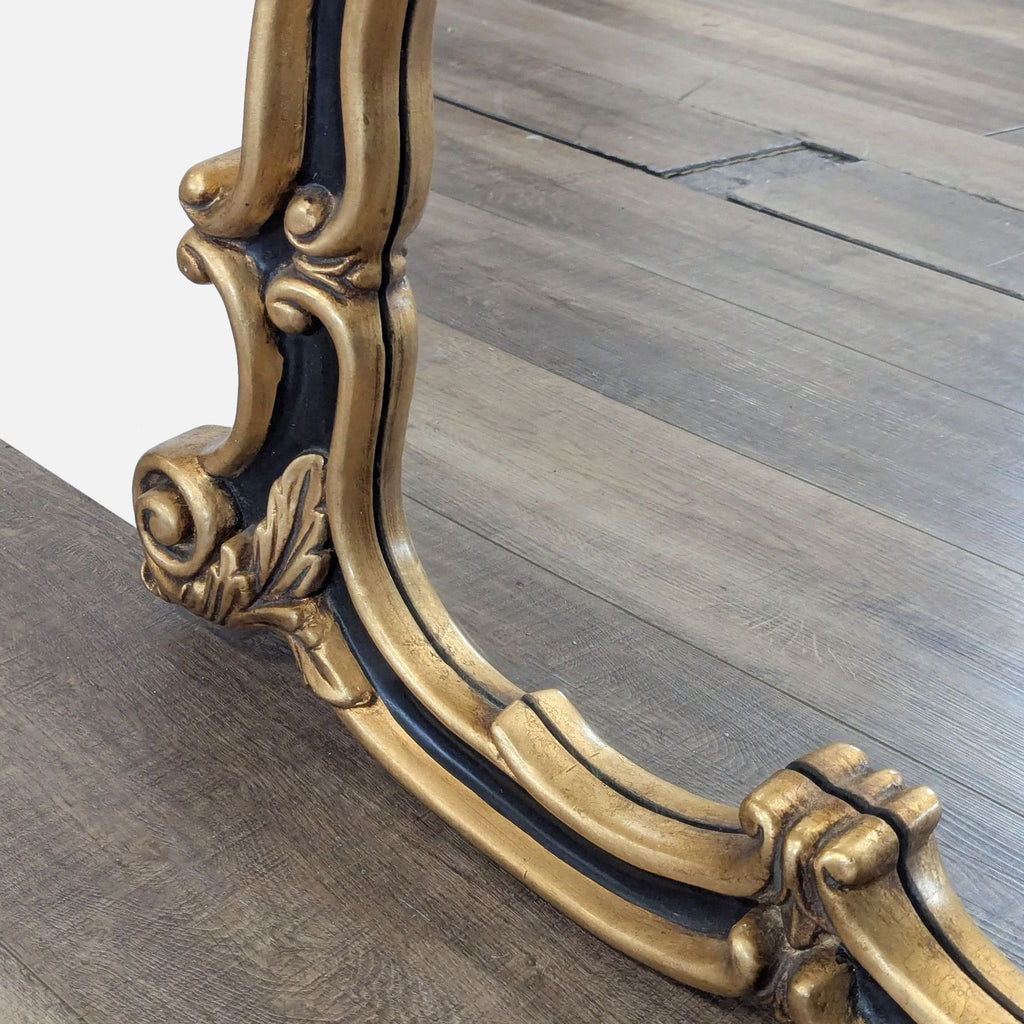 3. Bottom corner of the Reperch mirror, highlighting the curved black and gold frame with ornate leaf motif.