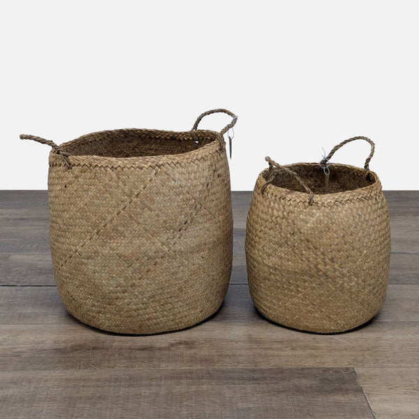 Two round woven seagrass baskets with handles from Creative Co-Op are displayed on a wooden floor.  