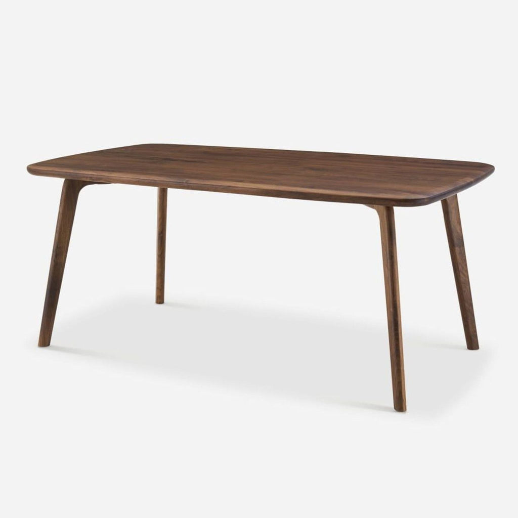 2. Angled side view of a Castlery dining table made from solid American walnut with smooth edges and wooden legs.
