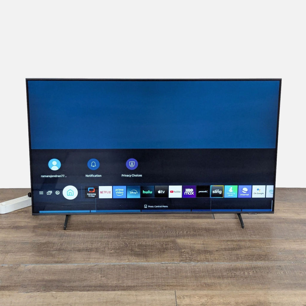 Front-on view of a Samsung 55-inch QLED 4K Smart TV with Smart TV interface apps shown on screen.  