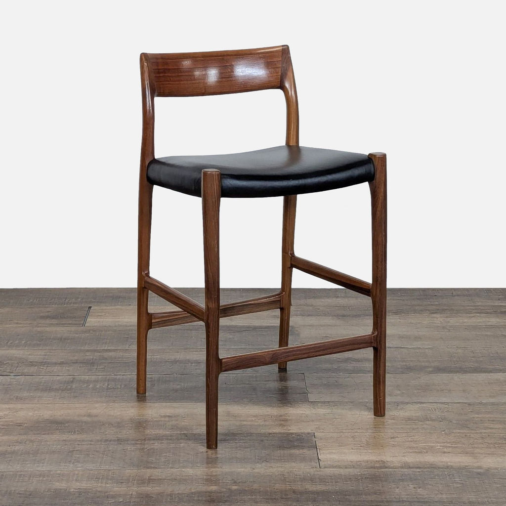 3. Angled side view of the Møller walnut stool featuring a curved backrest and black leather seat, made in Denmark.