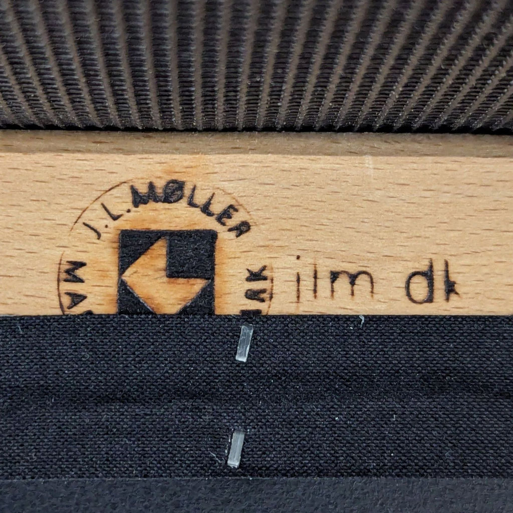 2. Close-up detail showing the J.L. Møller manufacturer’s stamp and hallmark on the underside of the stool.  