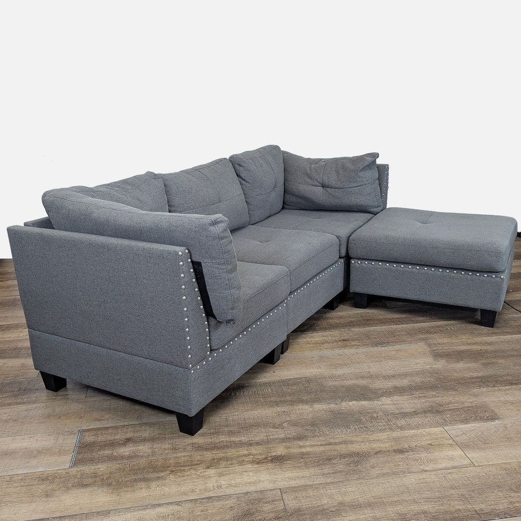 2. Side angle of a gray upholstered sectional by Amazon, showing decorative nailhead trim and movable ottoman.
