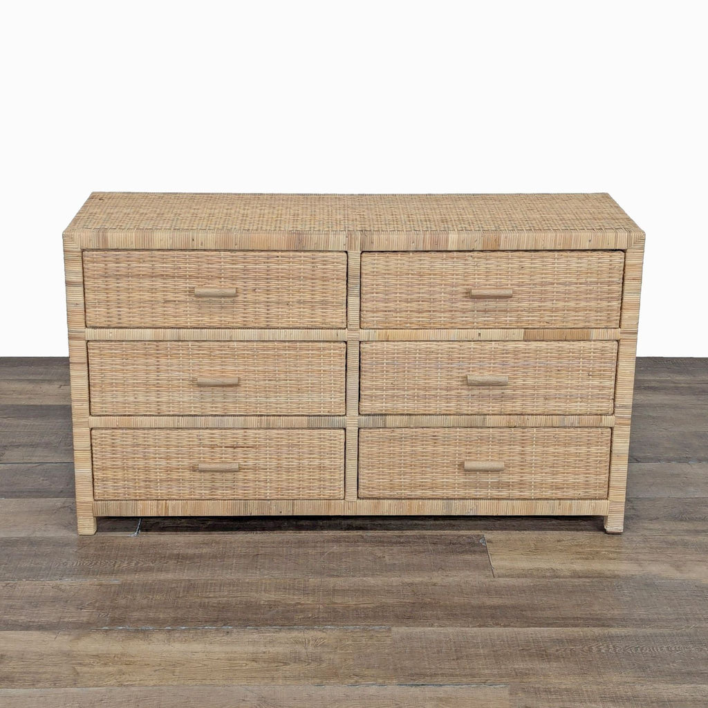 Woven rattan dresser with six drawers and wood frame, shown on a wooden floor against a white background.  