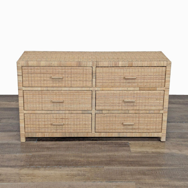 Woven rattan dresser with six drawers and wood frame, shown on a wooden floor against a white background.  