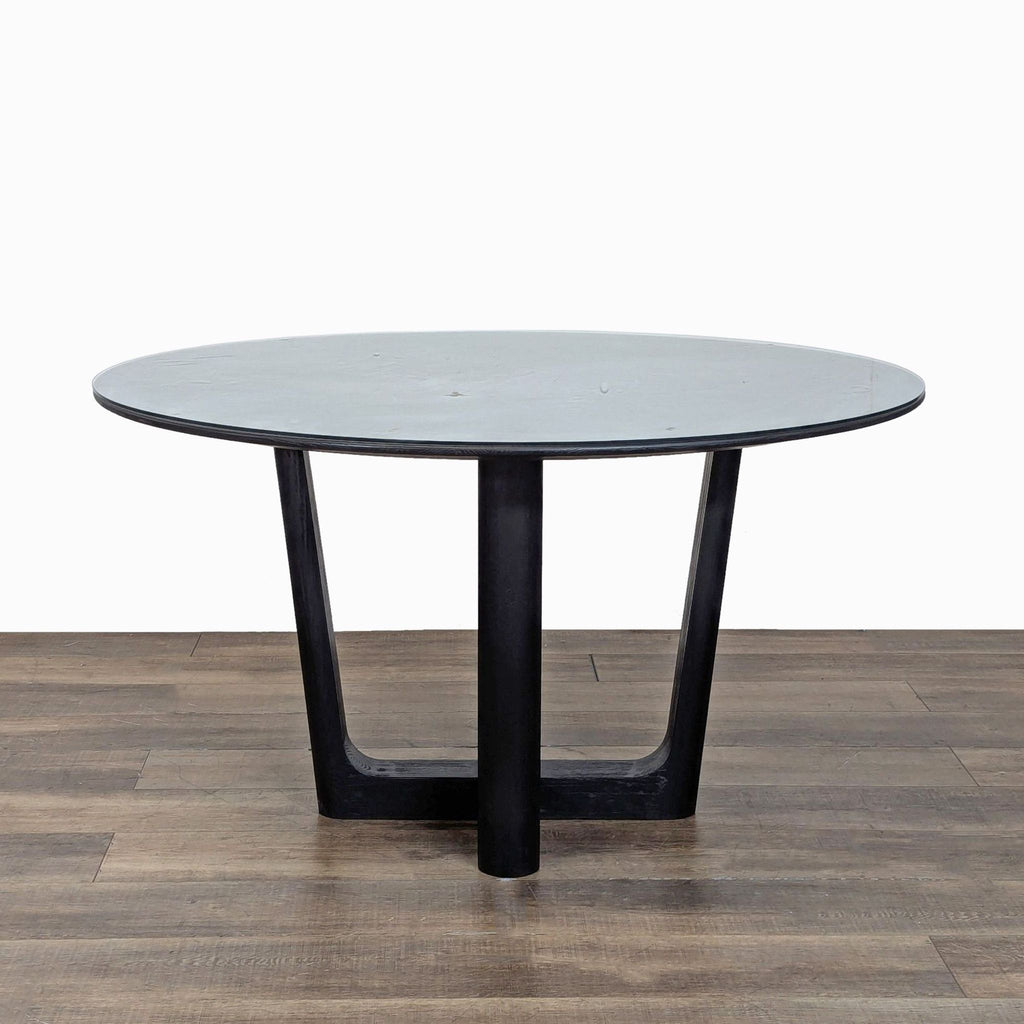 2. Close-up of Arhaus solid wood round dining table with black base and glass protective top, in Dining Set.