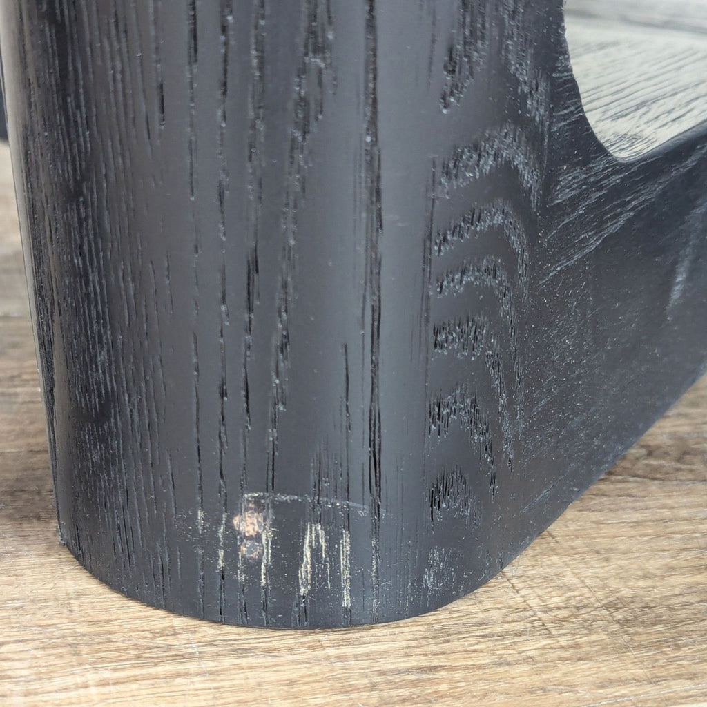 3. Detail of black wood leg from Arhaus dining table, showing wood texture and minor scuff at the base.