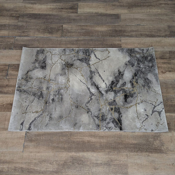 1. Safavieh Craft grey and gold area rug with a marble-like abstract design on a wooden floor.  