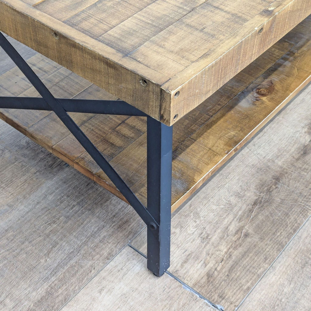Close-up of the Reperch coffee table’s corner, detailing the planked wood top, shelf, and black metal frame.