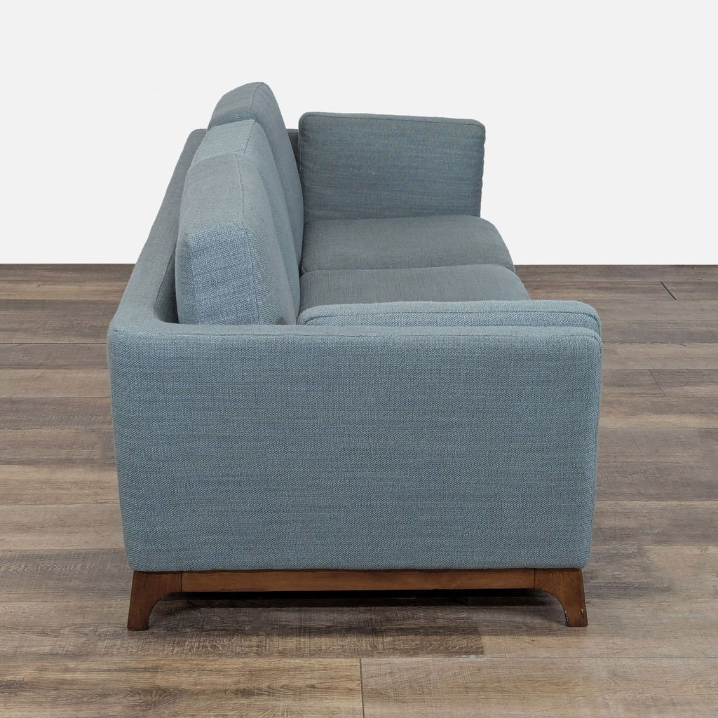 2. Side view of the Article 3-seat sofa showing its track armrest design and wooden base.