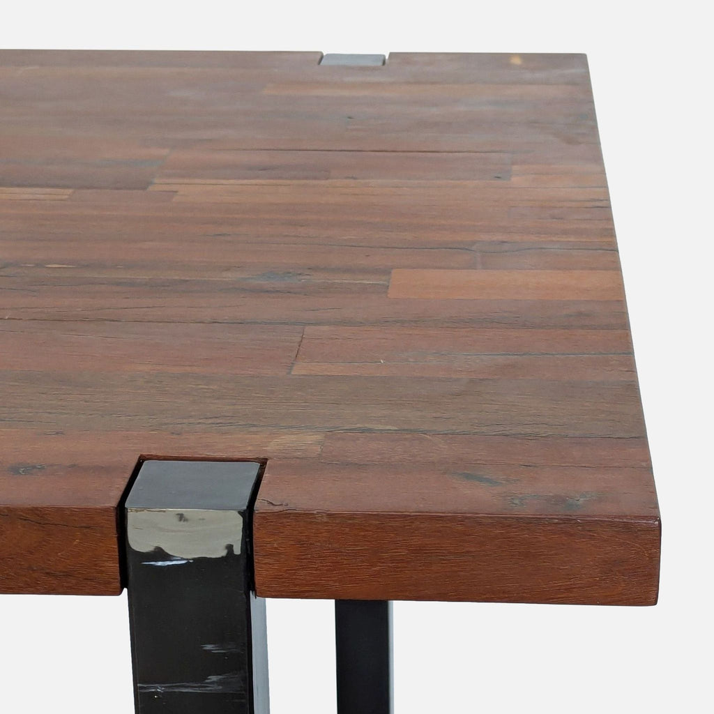 2. Close-up of CB2 dining table's corner showing dark wood grain and black metal leg detail.