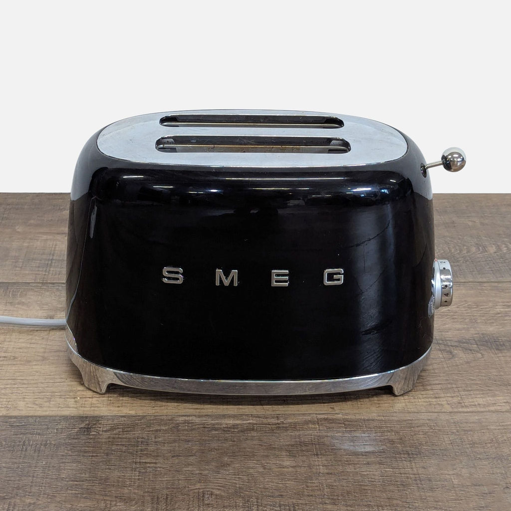 1. Front view of a black Smeg 2-slice toaster with a retro design, shown on a wooden countertop.  