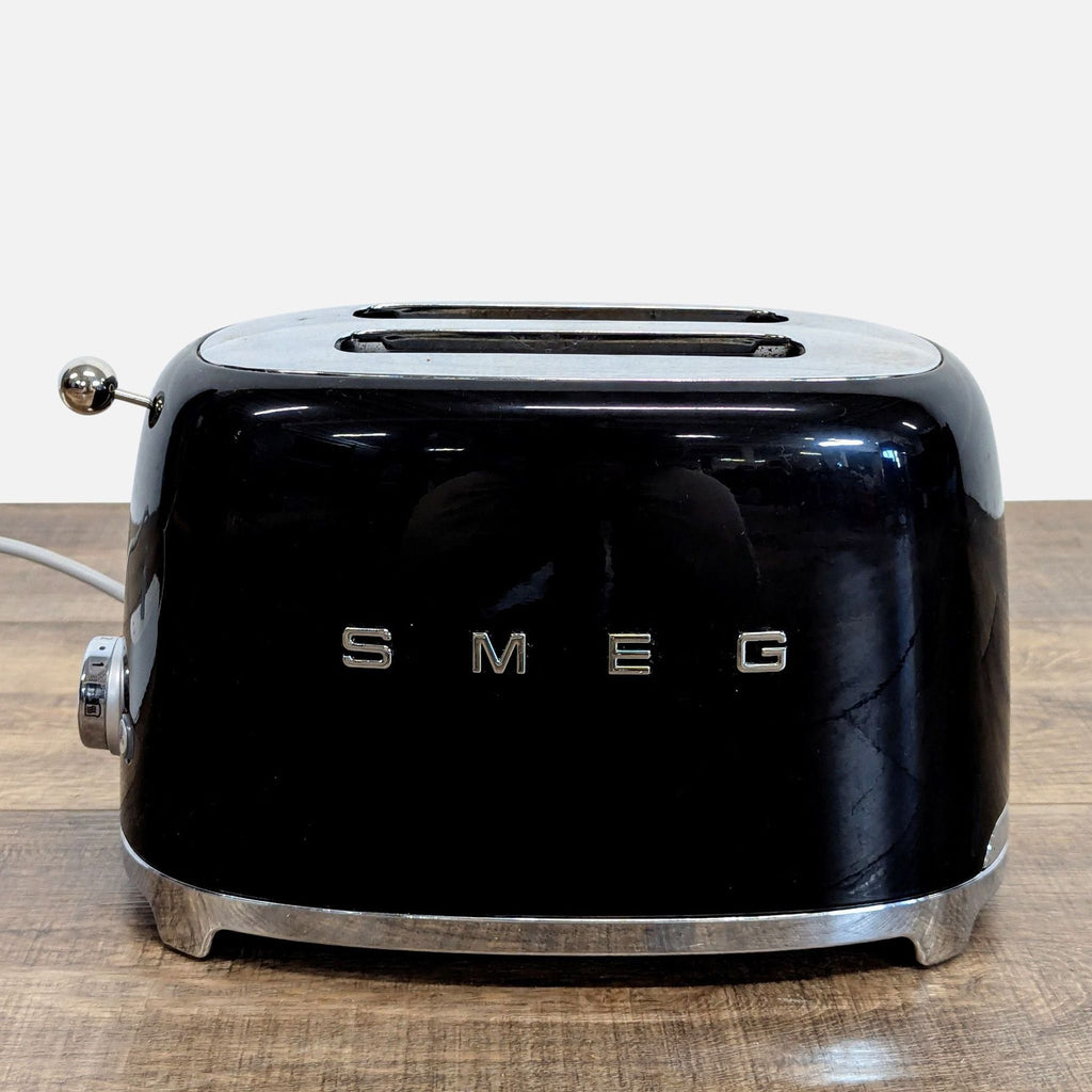 2. Angled side view of a compact Smeg black toaster, showcasing its chrome accents and two slots.  