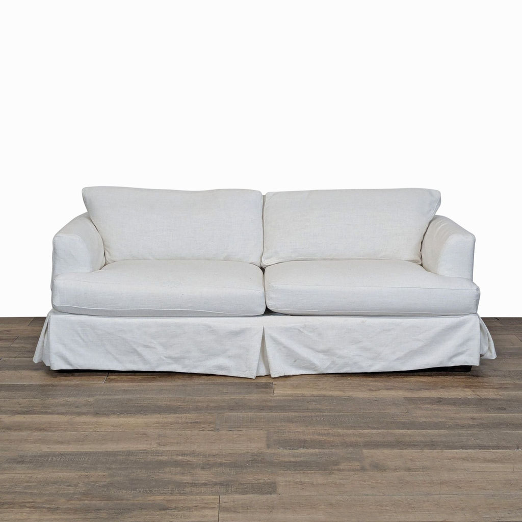 1. Joss & Main 3-seat sofa with wood frame, tailored dressmaker skirt, and soft slipcovered cushions, front view.