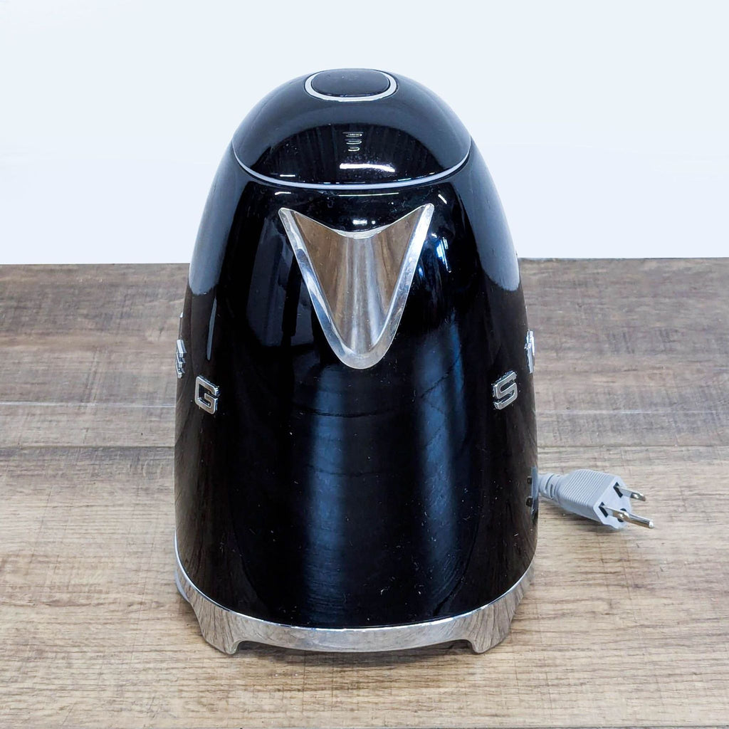 Side view of the Smeg black retro electric kettle, displaying stainless steel spout and chrome base detailing.