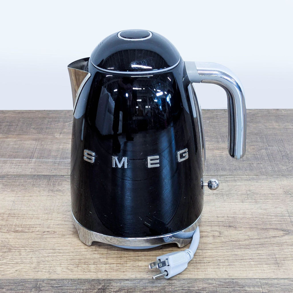 Smeg black electric kettle showing the chrome handle and power cord, highlighting retro-inspired design.  