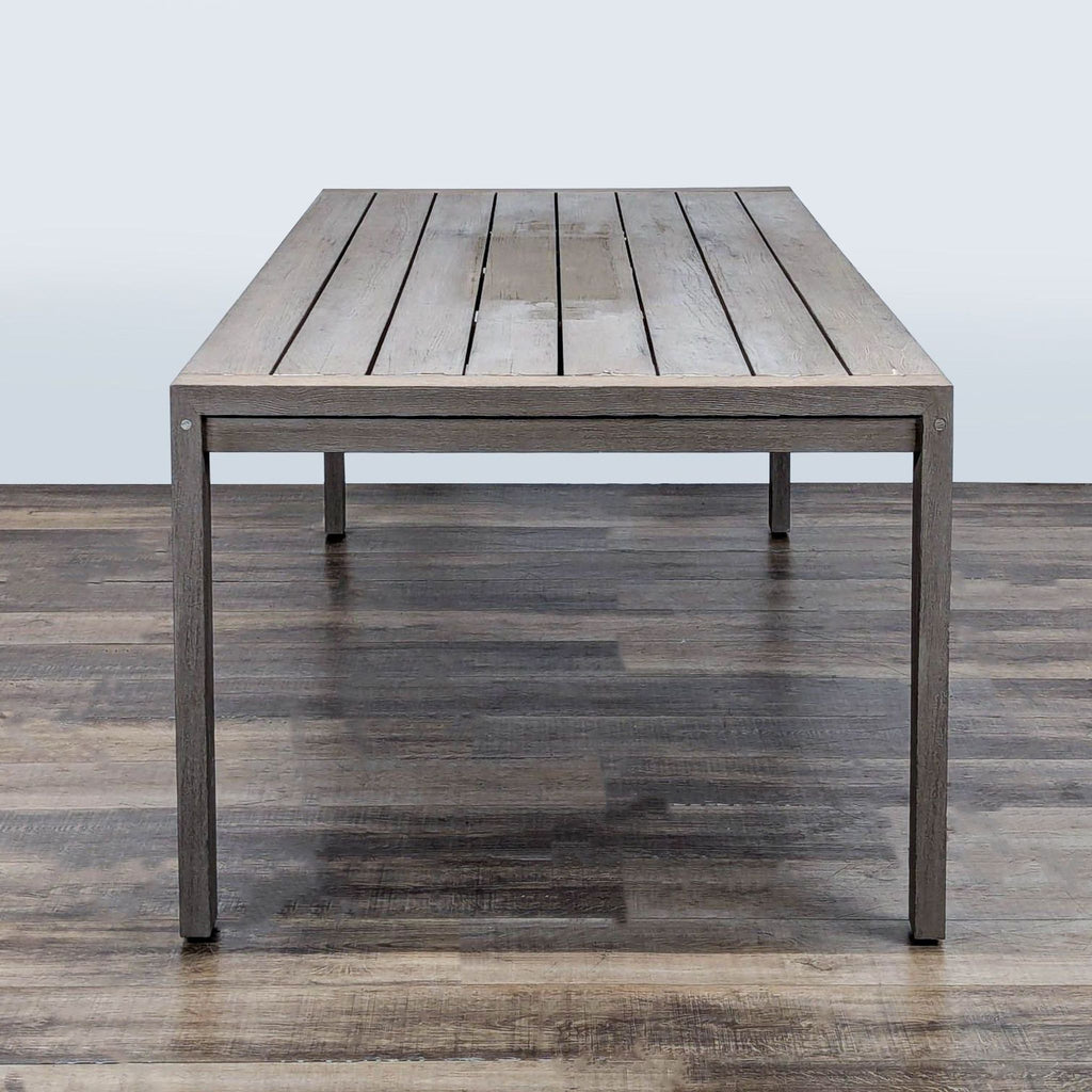 2. Restoration Hardware planked top teak table, sturdy square legs, shown from the short end, on wooden flooring.