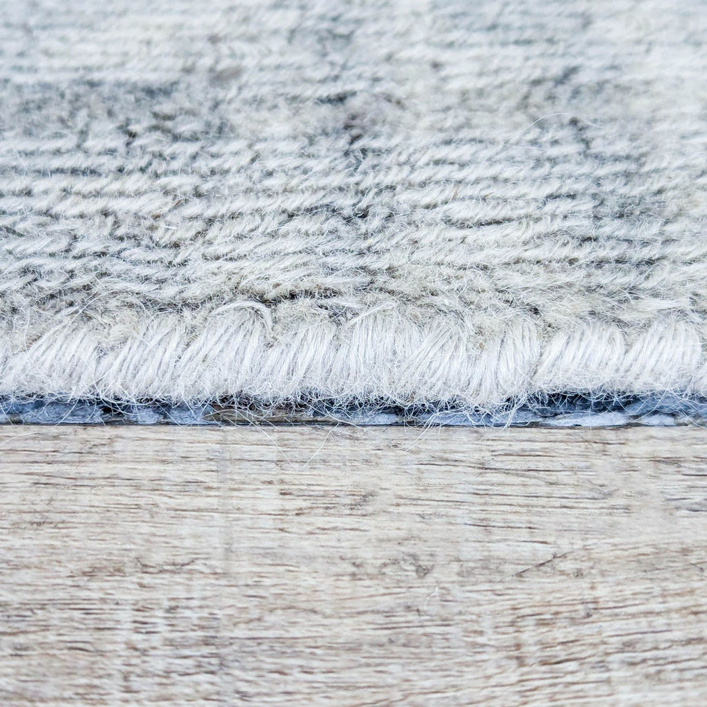 3. Side view highlights the thick, handwoven wool pile and sturdy, textured edge of the Pottery Barn rug.