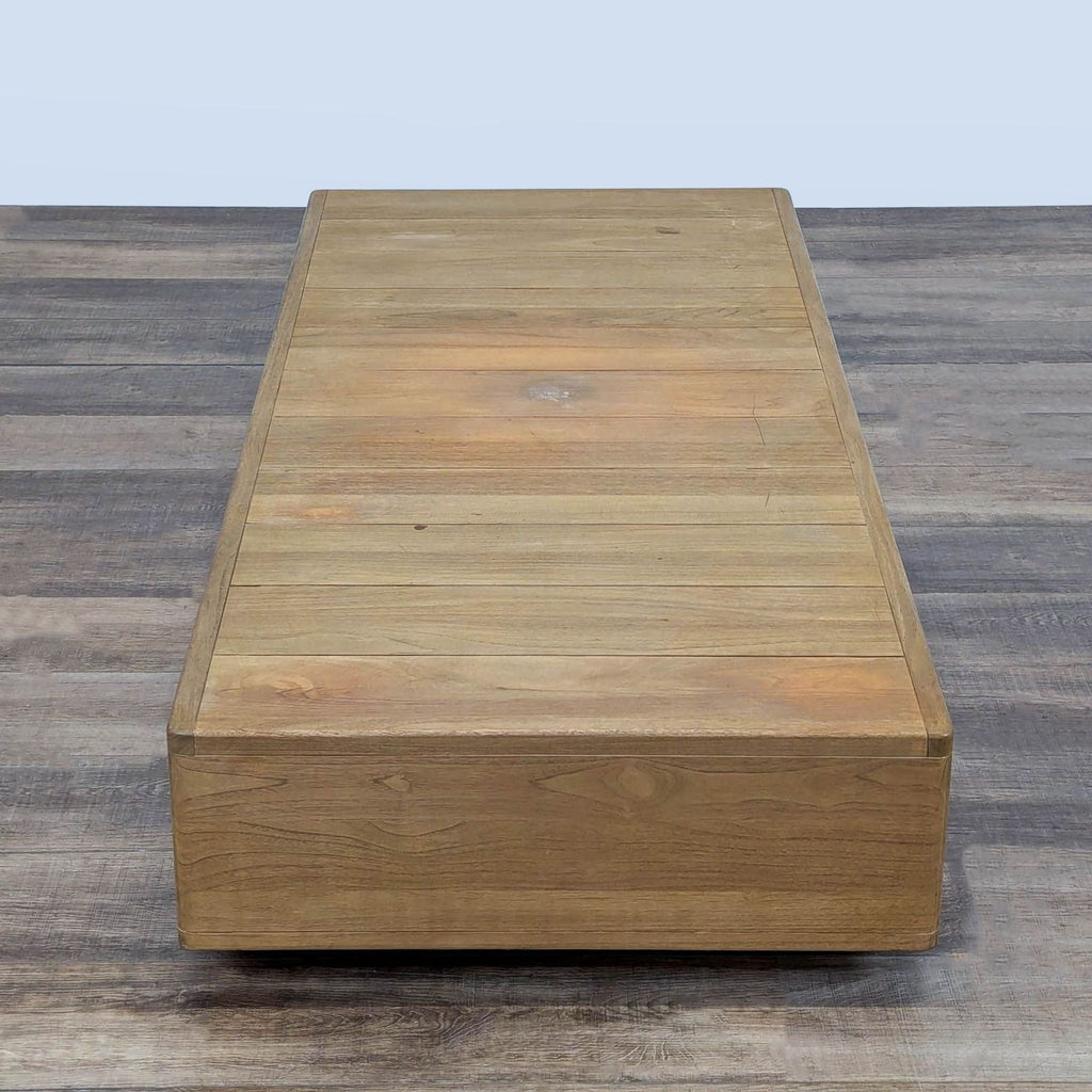 3. Minimalist solid teak plank-top table from Restoration Hardware, viewed from the end, on a wood floor.